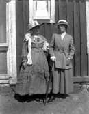 Maria Berg och jungfrun Augusta Johansson iförda kläder sydda av fröken Zetterman, Axvall.

Fotografen Maria Berg född Flach.

Kapten Sigge Flachs samling, Prinshaga, Axvall.