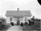 Exteriör. 
Två damer med ett barn och herre med häst framför litet vitt hus med glasveranda. 
Gullspångssamlingen.
Bilder från Gullspång med omnejd.