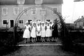 Fru Håkansson med elever vid Hushållsskolan, Stridsborg i Kvänum.
Huset bakom flickorna kallades Långholmen.
Här hade sadelmakare E H Norman lokal.