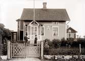 Postkontoret o föreståndare Johansson med fru framför huset, som har Postens skylt på väggen.