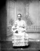 Ateljé. Dam med litet barn i knäet.Fotograf: Ellen Kock? Axel Lundbäck m.fl.Gullspångssamlingen.Bilder från Gullspång med omnejd.