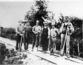 L.S.S.J. 
(Lidköping-Skara-Stenstorps Jernväg).
Omkring år 1920 togs den här bilden av ett så kallat putsarelag på LSSJ. 
Fru Allida Sjöberg har tagit bilden, då boende i Källby. Hennes far ses som tvåa från vänster. Det gällde på den tiden att hålla järnvägsbanken ren och fri från ogräs och därför sändes regelbundet putsarelag ut för att rensa upp. 
Laget arbetar här på sträckan Vinninga - Skara under ledning av banmästare A. Skog i Skäggatorp. 
På bilden ses från vänster: 
Johan Svensson, Österbäcken, Händene.
S.G. Fred, Fredsborg, Händene.
Albert Karlsson, Ekåsen, Hasslösa.
Johan Gustavsson, Nya Ledet, Hasslösa.
August Skog, Skäggatorp.