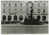 Eoska huset på Larmtorget. Storgatan i förgrunden. Vasabrunnen av Nils Sjögren föreställandes David och Goliat på pelaren.