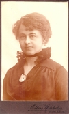 Visitkort, bröstbild av Ellen Warholm i svart klänning och svart spetskrås kring halsen samt kamébrosch.