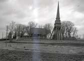 En klockstapel, kyrkogård och kyrka. Pelarne kyrka.