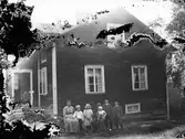 Familjegrupp framför hus.
