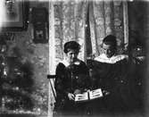 Två kvinnor tittar i ett fotoalbum.