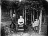 Kvinna i folkdräkt och två pojkar i skogsmark, Dalarna