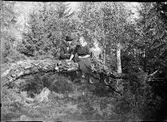 Josef, Sara och Tyra sitter på en trädstam i skogen, Östhammar, Uppland