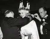 Två män ger Lucia ett smycke.