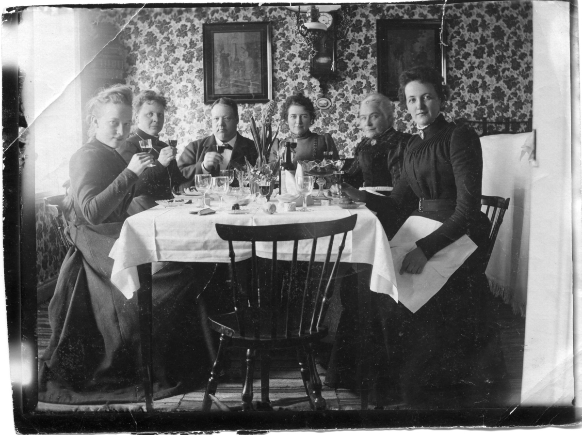 Calla Helena Sundbeck, Kalas. På snarlik bild står antecknat "Lyckönskan till Amalia 20/4 1900". Man firar sannolikt Ida Amalia Eriksons namnsdag som inföll detta datum. Den tomma stolen tillhör sannolikt fotografen Calla Sundbeck. Fr v: okänd, Ida, Knut, Julia, Wilhelmina, Selma Ida Amalia var dotter till polkagristillv…