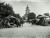 Torghandel med kyrka i bakgrunden, okänd stad.