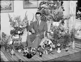 Man i bostadsmiljö omgiven av blommor, Östhammar, Uppland