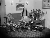 Kvinna i bostadsmiljö omgiven av blommor, Östhammar, Uppland