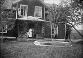 Sannolikt midsommarfirande, Ruben, Christiane och Marit Liljefors står på verandan till Svensgården, Leksand, Sverige omkring i början av 1920-talet