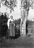 Christiane Liljefors, iklädd folkdräkt, troligen Leksandsdräkt, står vid björkar, Dalarna