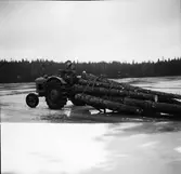 Traktor med timmerlass på isen över Ärsjöarna vid Kantabur västerskog. Mannen på traktorn är Ivar Karlsson i Vagnabäck.