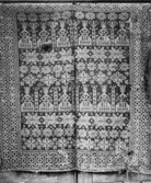 Täcke som i spegeln innehåller rader av fåvitska (oförståndiga) jungfrur med sina tända facklor och visa jungfrur längre ner med släckta facklor, stjärnor samt olika rosor. Bården har återkommande geometrisk form. Två vävda våder ihopsydda till ett täcke. Åtskilliga skador.