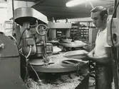 Interiör, Hushållsporslinsfabriken. Maskinell tallriksformning.
Personer: Sergio Mineni