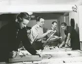 Interiör, bostadshotellet på Mariagatan 13. Unga män i färd med att utöva träslöjd i slöjdverkstad  för fritidsaktiviteter.
Personer: Slöjdlärare Thure Persson, nr två från höger