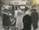 Interiörbild. Svenskt i Topp. Gustavsbergs Fabriker demonstrerar tillvägagångssättet vid porslinsdekor. Turné ute i landet, sannolikt i samarbete med kooperationen i Sundsvall. Plats: Varuhus.
Personer: Nils Hellqvist från Gustavsbergs Fabriker och okända personer..