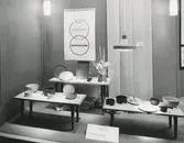 Interiörbild. Utställning av hushållsporslin i stengods från Gustavsbergs Fabriker. Arrangerad av Landsföreningen Dansk Konsthantverk, Charlottenborg, Danmark. Lokal okänd.