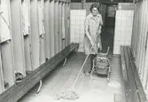 Interiör. Städerska i omklädningsrum, Hushållsporslinsfabriken.
Personer: okänd