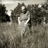 Persgårds-Anna i Hugalyckan sitter på en trädgårdsstol i högt gräs. Hon föddes 1895 i torpet Flyerna i Borshults by i Svartrå socken, men gifte sig med Teodor Johansson Persgård och de fick fem barn. I Hugalyckan bodde också systerdottern Anna-Lisa.