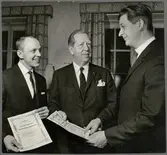 Trafikaktiebolaget Grängesberg–Oxelösunds Järnvägars dåvarande direktör Anders Rolfsman delar ut varsin aktie till J L Ekegård och P-O Larsson som belöning för deras förslag rörande lameller till snöslungor.