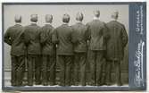 Ateljéporträtt - Sju män iklädda kostym, porträtterade bakifrån. Männen är: Harald Falk, David Nylund, Elias Stenius, Yelverton Tegner, Manne Ekman, Albert Falk samt en oidentifierad man, Uppsala 1902