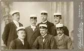 Ateljéporträtt - Sju män iklädda kostym och studentmössa. Harald Falk stående som andre man från vänster, Uppsala 1903