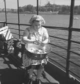 Kvinna skrapar potatis ombord på en båt.