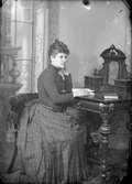 Ateljéporträtt - kvinna vid skrivbord, Uppsala före 1914