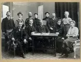 Gruppbild av 5 kvinnor och 6 män, sittande och stående, i en halvcirkel vända mot kameran. Främst ett litet arbetsbord med pappershögar och penna. Kommitté för nykterhetskurs, år 1909.

Stående från vänster: 
Herr Ander
Snickare Larsson
Fröken Östergren (gift Norén) 
Målarmästere Hinze
Fru Mothéus

Sittande från vänster: 
Kakelugnsmakare J.A. Jonsson
Skräddare Jakobsson
Handlare K.P. Wessman
Fröken Lina Larsson
Fröken Matheus