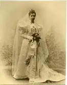 Bruden Maggie Täcklind i sin brudklänning med brudbuketten i höger hand.

Maggie Täcklind.
Född Brown den 28 november 1874 av bruksägaren Mauritz Brown och hans hustru Anna Lindqvist. Gift den 4 november 1896 i Stockholm med vice häradshövdingen, sedan häradshövding i Vättle, Ale och Kullings domsaga Magnus Johan Täcklind. Död i Alingsås den 9 augusti 1923.