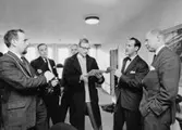 TV-aktuellts fotograf, längst t.v. och redaktör Gary Engman (med glasögon) samtalar med postbankschefen Sven Lönnqvist längst t.h. och förste byråsekreterare Thord Hammarberg. I bakgrunden står byrådirektör Harry Wicksell, t.v. och avdel-ningschef Per Åke Törnqvist.
