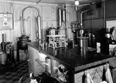 Bilden visar laboratoriet på apoteket Hjorten. Rummet är fyllt med olika maskiner som apoteket anväde för tablettillverkning och/eller andra ändamål.