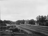 Bangård och stationshus vid Emmaboda järnvägsstation. Personalen står på perrongen. Godsmagasinet till vänster.