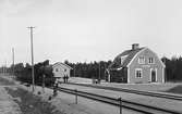 Enånger järnvägsstation, på spåret syns ett tåg från Ostkustbanan, OKB. På gårdsplan syns en kärra märkt med OKB.
Trafikplats anlagd 1926. En- och en halvvånings stationshus i trä
