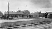 Järnvägsstationen i Eslöv. Bilden tagen i samband med, eller strax före, invigningen av det nya stationshuset 1915, därav utsmyckningarna.
Till vänster i bild syns ett pågående arbete vid plattformen.
Notera att flaggorna ser inverterade ut, detta är en bieffekt av den typ av film, ortokromatisk film, som användes vid den här tiden.