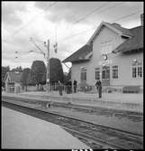 Resande och stationskarl utanför Gårdsjö station. I bakgrunden flaggas det på halvstång.