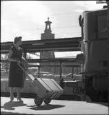 Transport av resväska på Centralstation. Stockholms stadshus i bakgrunden