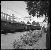 Mjölby station med rosplantering. D-lok med personvagnar på stationen. Resgodsvagn SJ F04.