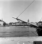 Persontåg på väg över Riddarholmsbron, mellan Riddarholmen och Mälarstrand. Fotot taget från Söder Mälarstrand. Stockholms Domkyrkas (Storkyrkan) torn i bild.