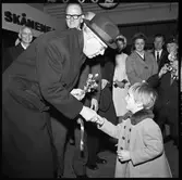 Invigning av Årsta partihandel. Kung Gustav VI Adolf får blommor av liten flicka