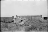 Resterna av en förstörd pansarvagn framför godsvagnar.