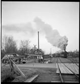 Bil vid järnvägskorsning inväntar ångtåg.