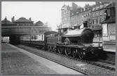 Ånglok med personvagn på station.