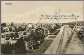Stationsmiljö i Vansbro med vagnar och stad i bild.
