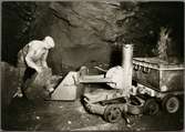 Gruvarbetare lastar ett stenblock på en tryckluftdriven lastmaskin.